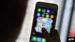 FILE - A woman looks at social networking apps Facebook, Instagram, Snapchat, Whatsapp, Twitter, Messenger and Linkedin on a smartphone, March 22, 2018.