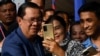 Cambodia's Prime Minister Hun Sen (L) takes selfies with people during a groundbreaking ceremony for the construction of a 135km expressway from the capital Phnom Penh to Bavet city in Svay Rieng province on the Cambodia-Vietnam border, in Phnom Penh on June 7, 2023.
