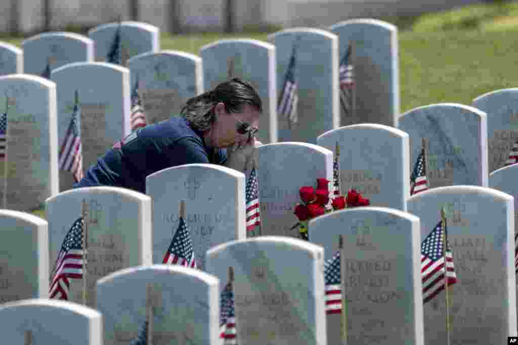 Rachel Owen lays her head on the grave marker of her grandparents, Army veteran Carl Herington and his wife, Carol, during a Memorial Day visit to the Sacramento Valley National Cemetery in Dixon, California, May 27, 2024.
