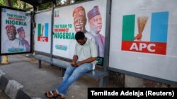 Un homme est assis à un arrêt de bus décoré d'affiches de campagne du candidat à la présidence du All Progressives Congress (APC), Bola Tinubu, avec son colistier Kashim Shettima à Lagos, au Nigeria, le 31 janvier 2023.