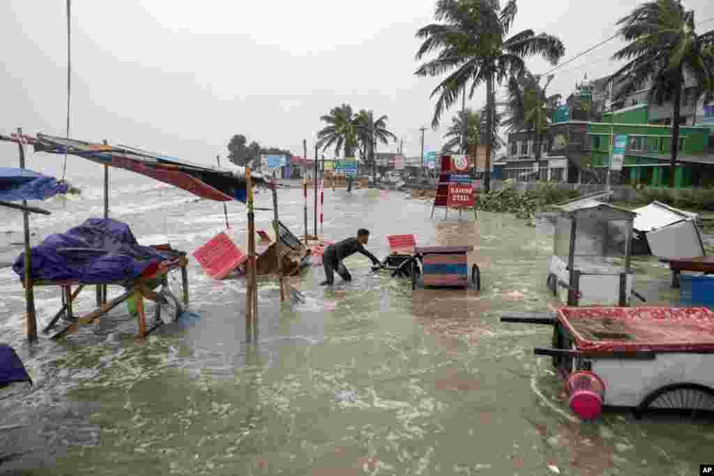 A man salvages a cart as water flows on to the Kuakata beach on the coast of Bay of Bengal caused by the advancing Cyclone Remal in Barisal, Bangladesh.