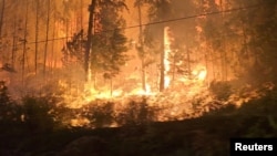 Fire burns close to a highway near Sorrento, British Columbia, Canada, on Aug. 18, 2023, in this screen grab obtained from social media video. (Nikki Goyer via REUTERS)