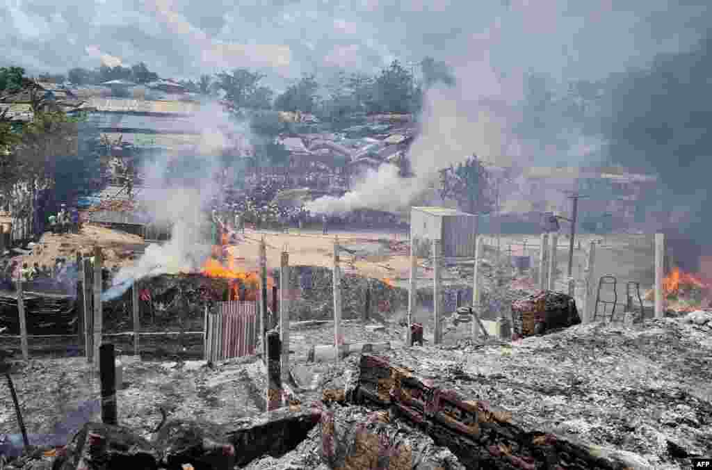 Rohingya refugees look through the debris of their houses charred by a fire at the Ukhia camp in Cox's Bazar.