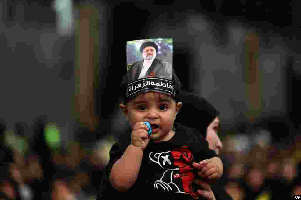 A child carried by a woman wears a picture on his head of Iran's late president Ebrahim Raisi during a rally to mourn the death of the Iranian president and his entourage killed in a recent helicopter accident, in Beirut's southern suburbs.