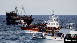 FILE -Boti ya walinzi wa pwani ya Italia ikiwa imebeba wahamiaji waliookolewa baharini ikipita katikati ya boti za utalii, katika kisiwa cha Sicilian, Lampedusa, Italia, Sept. 18, 2023.