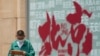 ARCHIVO - Un niño navega por una tableta mientras camina junto a un cartel que promociona destinos turísticos en Beijing el 19 de julio de 2023. China reabrió completamente sus puertas a los turistas en marzo.