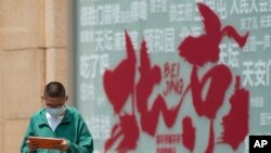 ARCHIVO - Un niño navega por una tableta mientras camina junto a un cartel que promociona destinos turísticos en Beijing el 19 de julio de 2023. China reabrió completamente sus puertas a los turistas en marzo.