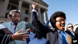 El representante estatal Justin Jones, demócrata de Nashville, y el representante expulsado Justin Pearson, demócrata de Memphis, levantan la mano justo antes de que Jones preste juramento frente al Capitolio estatal el lunes 10 de abril de 2023 en Nashville, Tennessee.