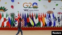 2023年9月8日，新德里G20峰会前，一名男子在会员国国旗前走过。