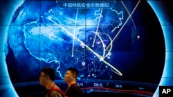 Sejumlah pengunjung berjalan melewati layar yang menunjukkan jumlah serangan siber yang terjadi di China dalam acara Konferensi Keamanan Internet China di Beijing, pada 12 September 2017. (Foto: AP/Mark Schiefelbein, File)