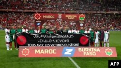 Des joueurs marocains et burkinabés tiennent une banderole en solidarité avec les victimes du séisme, France, le 12 septembre 2023.