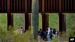 Migrantes atraviesan compuertas del muro fronterizo entre EEUU y México en el sector de Tucson, Arizona, el 29 de agosto de 2023.