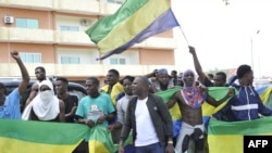 Des habitants brandissant des drapeaux nationaux du Gabon font la fête à Libreville le 30 août 2023.