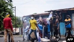 Des partisans de l'opposition détruisent une image publicitaire du président sortant des Comores Azali Assoumani, lors d'une manifestation à Moroni le 17 janvier 2024, suite à l'annonce des résultats de l'élection présidentielle.