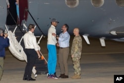 El director de lucha contra el terrorismo, David Cotter (izq), el enviado presidencial para asuntos de rehenes, Rodger Carstens y el coronel Mark Davis, saludan al estadounidense liberado Savoi Wright cuando sale de un avión, el 20 de diciembre. 2023, en San Antonio, Texas.