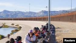 Migrantes de Venezuela, sujetos al Título 42 y dudosos de pasar a EEUU, esperan junto a personas de otras nacionalidades que hacen fila para ser procesados por la Patrulla Fronteriza estadounidense en El Paso, Texas, el 4 de enero de 2023.