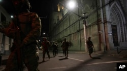 Soldiers walk towards a vehicle that blew up outside the Women´s and Human Rights Ministry building in Quito, Ecuador, Aug. 30, 2023. The building used to house the National Service for Attention for People Deprived of Liberty, which runs the jail system.