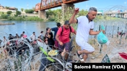 Migrantes cruzan de manera irregular sobre el alambre de púas hacia Eagle Pass, Texas, con la intención de ser procesados por autoridades fronterizas el 25 de septiembre de 2023.