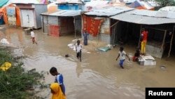 Somali children wade through floodwaters outside their makeshift shelters following heavy rains at the Al Hidaya camp for the internally displaced people on the outskirts of Mogadishu, Somalia, Nov. 6, 2023