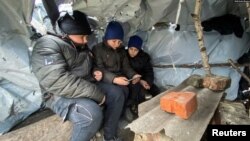 Niños ucranianos asisten a una clase en línea en un aula construida por ellos mismos con postes de madera y láminas de plástico en una aldea de la región de Járkov.