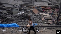 Palestinsko dijete hoda s biciklom pored ruševina zgrade nakon što je pogođena izraelskim zračnim napadom, u gradu Gaza, 8. oktobra 2023.