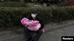 北京一家儿童医院外一名男子怀抱一个幼童。（2023年11月27日）