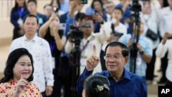 2023 年 7 月 23 日，柬埔寨首相洪森（右）与妻子文·拉尼（左）在柬埔寨金边东南部塔克穆阿的一个投票站投票后，展示了沾有墨水的手指。
