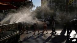 People walk along the Las Vegas Strip in the heat, July 13, 2023, in Las Vegas.