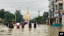 អ្នក​ស្រុក​ដើរ​កាត់​ផ្លូវ​លិច​ទឹក​ក្បែរ​វត្ត Shwe Maw Taw ក្នុង​ក្រុង Bago ចម្ងាយ​ប្រហែល​៨០ គីឡូម៉ែត្រ ភាគ​ឦសាន​ទីក្រុង​រ៉ង់ហ្គូន ប្រទេស​មីយ៉ាន់ម៉ា ថ្ងៃទី៩ ខែ​តុលា ឆ្នាំ២០២៣។