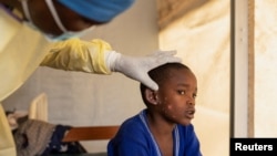 Le Dr. Tresor Wakilongo vérifie l'évolution des lésions cutanées sur l'oreille d'Innocent, atteint de Mpox au centre de traitement de Munigi près de Goma, province du Nord-Kivu, RDC, le 19 juillet 2024.