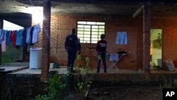 ARCHIVO - En esta fotografía publicada por la Policía Civil brasileña, agentes en el porche de una casa donde fue rescatada la madre del futbolista brasileño Taison, en Brasil, el 16 de julio de 2018.