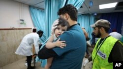 Yon doke Palestinyen kenbe yon timoun ki te blese nan yon atak ayeryen nan Gaza, Dimanch 22 Oktob, 2023.