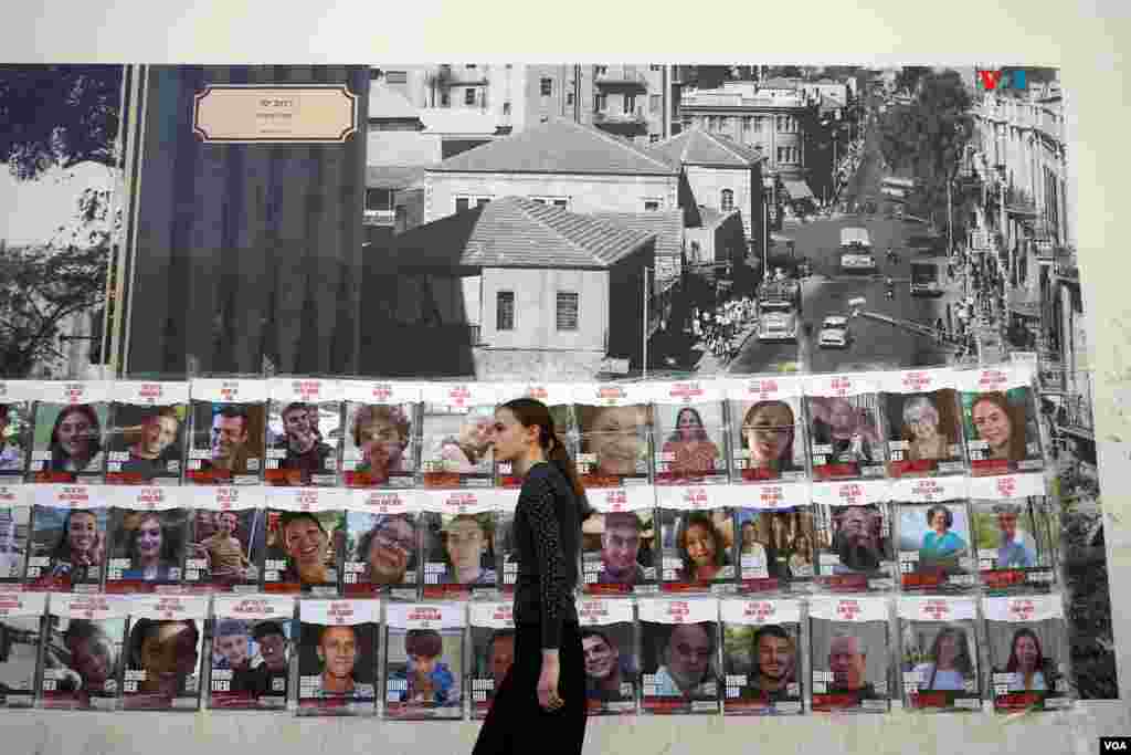 Una chica pasa junto a carteles con los rostros de los israelíes que permanecen aún en poder de Hamás.