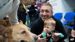 Un entrenador le muestra a un niño cómo jugar con un perro llamado Nike durante sesiones de terapia canina en Kiev, Ucrania, el jueves 26 de octubre de 2023.