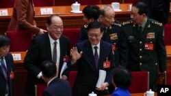 Hong Kong Chief Executive John Lee, center, waves to delegates after the opening session of the National People's Congress (NPC) at the Great Hall of the People in Beijing, March 5, 2024.