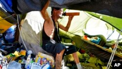 FILE - Charles Sanders, 59, sits in his tent inside a homeless encampment called 'The Zone,' July 14, 2023, in downtown Phoenix.