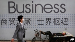 资料照 - 一位中国拉三轮工人在他的三轮车上休息。背景是一招商广告。