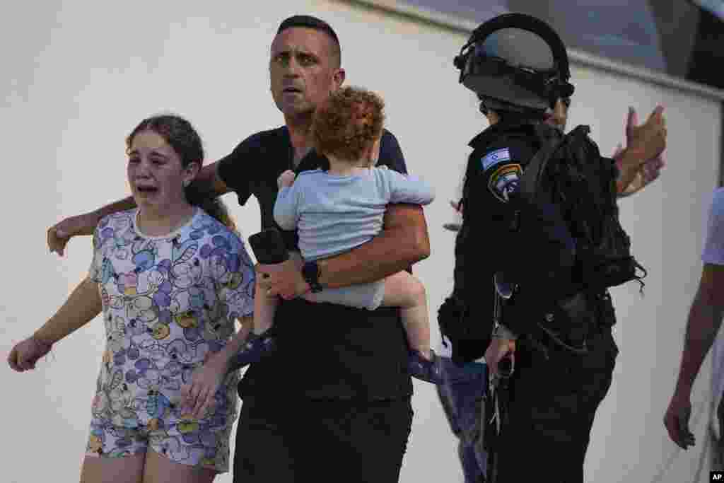 Israeli police officers evacuate a family from a site hit by a rocket fired from the Gaza Strip, in Ashkelon, Israel, on Oct. 7, 2023. The rockets were fired as Hamas announced a new operation against Israel.