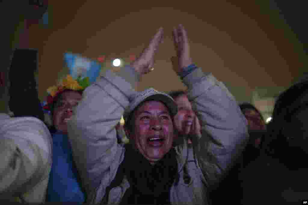 La gente celebra mientras mira la ceremonia de toma de posesión del presidente entrante de Guatemala, Bernardo Arévalo, en una pantalla afuera del Palacio Nacional en la Ciudad de Guatemala, en la madrugada del 15 de enero de 2024. (Foto AP/Santiago Billy) 