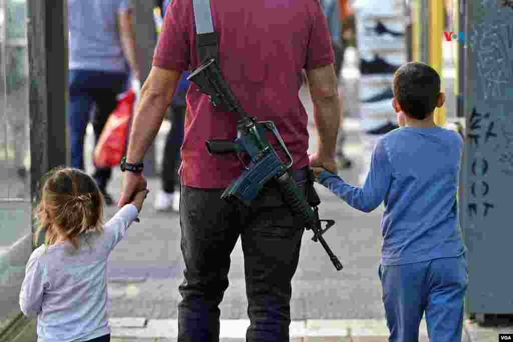 Un hombre armado con un M16 pasea con sus hijos en Jerusalén, pocas horas después del inicio del cese al fuego de cuatro días pactad entre Israel y Hamás.