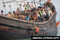 Pengungsi Rohingya yang baru tiba terdampar di perahu karena masyarakat sekitar memutuskan untuk tidak mengizinkan mereka mendarat setelah memberikan air dan makanan di Pineung, Aceh, 16 November 2023. (Foto: AMANDA JUFRIAN/AFP)