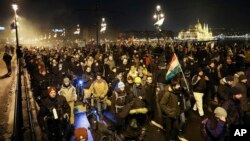 Anti-government demonstrators march across Margaret Bridge over the River Danube with the Parliament building in the background, in Budapest, Hungary, Dec. 16, 2018.