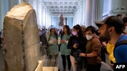 FILE - Visitors view the Rosetta Stone at the British Museum in London on July 26, 2022.