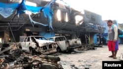 Seorang pria melihat kendaraan yang rusak di depan kantor Bea dan Cukai setelah kerusuhan di Jayapura, Papua, 30 Agustus 2019. (Foto: Antara/Indrayadi via REUTERS)