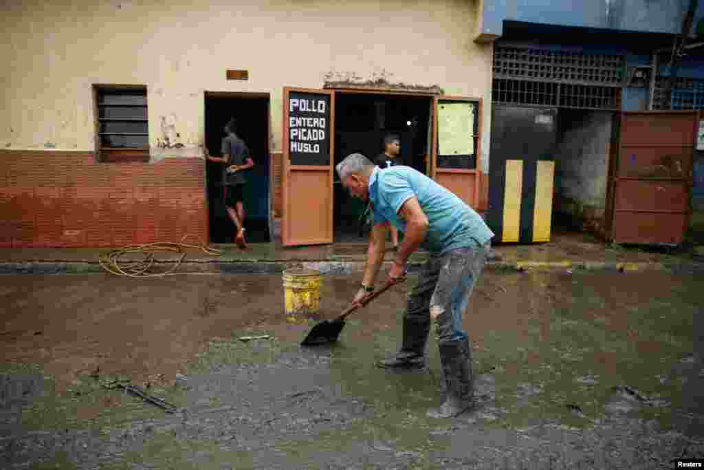 Habitantes del barrio Petare, en Caracas, ayudan a limpiar las calles llenas de lodo tras el desbordamiento del río Guaire.