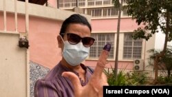 Eleitora residente em Luanda exibe dedo pintado depois de votar para as eleições gerais