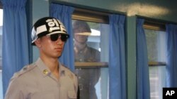 A North Korean soldier looks through a window as a South Korean stands guard at the U.N. truce village building that sits on the border of the Demilitarized Zone in Panmunjon, South Korea. (File)