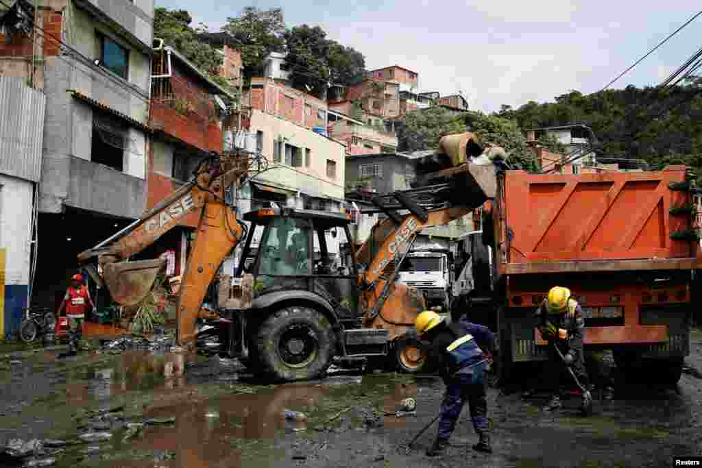 Bomberos voluntarios trabajan para remover el lodo de las calles.