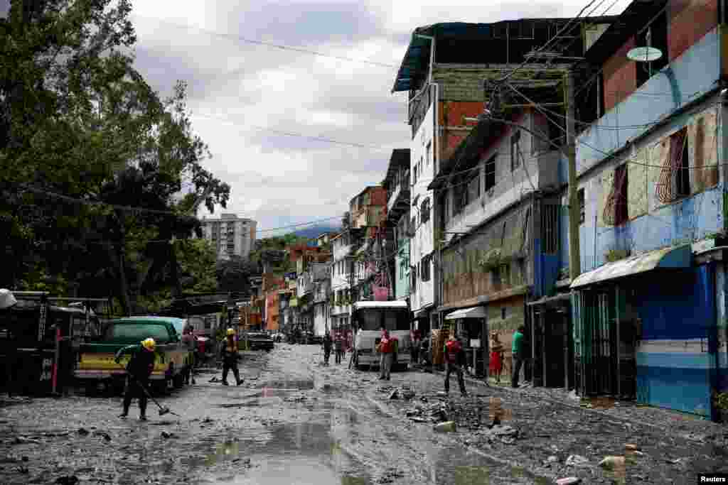 Las fuertes lluvias provocaron inundaciones en el barrio Petare, en Caracas. Bomberos voluntarios trabajan para quitar el lodo de una calle.