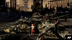 Stanovnici Kijeva prolaze pored ruskih vojnih vozila (Foto: AP/Evgeniy Maloletka)